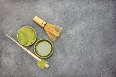 Kasede kibrit çayı. Tahta bir kasede yeşil kibrit çay tozu. Masada bambu çırpıcı ve kaşık var. Uzayı kopyala Düz yatıyordu. Siyah arkaplan