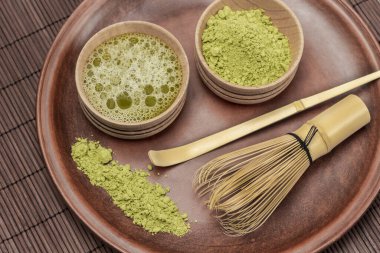 Kibrit çay tozu ve ahşap kaselerde çay. Seramik bir tabakta bambu çırpı ve kaşık. Düz yatıyordu 