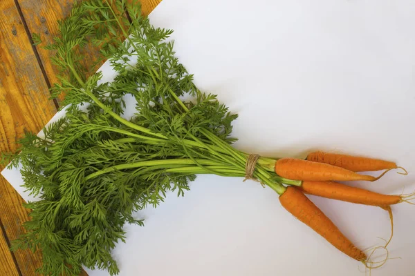 Bundle of carrots on a white and wooden background. Top view