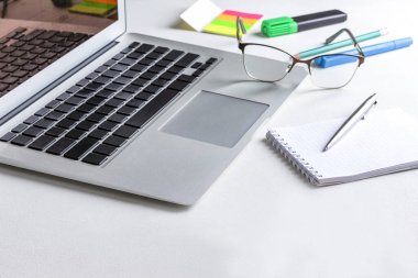 Laptop, defter ve kalem, bardaklar, kırtasiye malzemeleri masada. Evden çalışıyorum. Beyaz arkaplan.