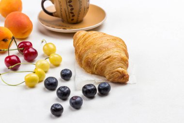 Kruvasan, kahve, kiraz ve yabanmersini. Üst görünüm, beyaz arkaplan, kopyalama alanı