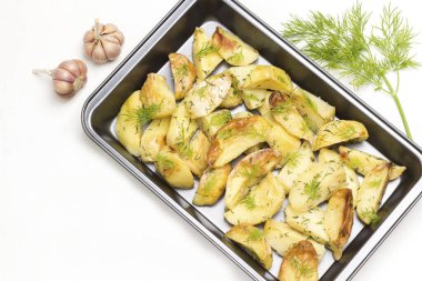 Yiyecek metal paletinde dereotlu kızarmış patates dilimleri. Sarımsak, yeşil biber kabuğu ve biberiye filizi. Beyaz arka plan. Düz yatıyordu