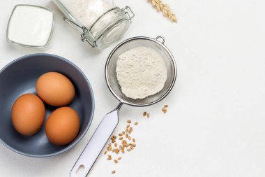 Tahta kaşık, elek ve cam kavanozda un. Beyaz arkaplan. 