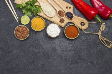 Farklı türde pirinç ve baharatlar. Tahta kesme tahtası. Çiğ Kırmızı Biber. Uzayı kopyala Düz yatıyordu. Siyah arkaplan