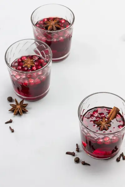 Hot winter drink with cranberries and spices. Star anise, cloves, pieces of brown sugar on table. Grey background. Top view