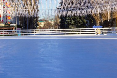 Kış buz pateni pistinde mavi buz. Üzerindeki ışıklar, uzaktaki ağaçlar..