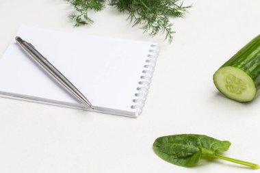 Ispanak yaprakları ve dereotu. Kalem ve defter. Beyaz arka plan. Üst yaşam