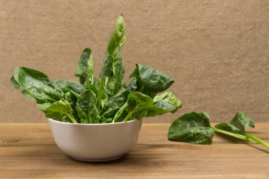 Beyaz kasede ıspanak. Hafif ahşap zemin. Üst görünüm. 