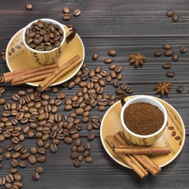 Kahve ve kavrulmuş kahve çekirdekleri. Tarçın tabağa yapışıyor. Kahve çekirdekleri ve yıldız anason masada. Karanlık ahşap arka plan. Düz la