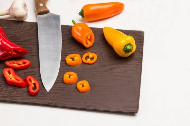 Kesme tahtasında dilimlenmiş biber ve bıçak. Yeşil kasede Mung fasulyesi. Beyaz arka plan. Üst görünüm