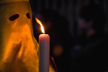 A person in a yellow costume stands next to a candle with the word  light  on it. clipart