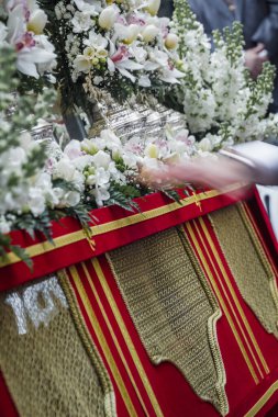 Bir adam üzerinde çiçekler olan bir masada çalışıyor..
