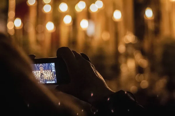 person taking a photograph with a compact camera at an Easter pass with lit candles