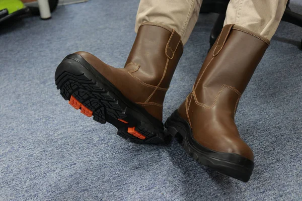作業者は茶色のブーツを使用し これらの安全靴は革で作られており 作業中に足を怪我から守るために使用されます ストック画像
