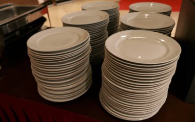 Stacks of plates and glasses on a table in a restaurant or hotel kitchen