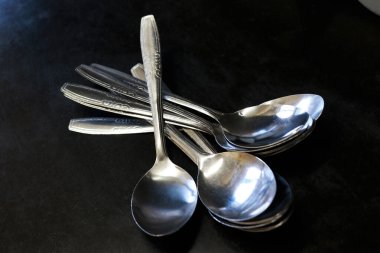 Bir ev ve restoranda mutfak masasında siyah bir arka plana karşı kaşık yığını.