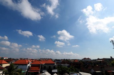 Açık mavi gökyüzü ve beyaz bulutları olan bir şehir manzarası