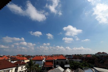 Açık mavi gökyüzü ve beyaz bulutları olan bir şehir manzarası