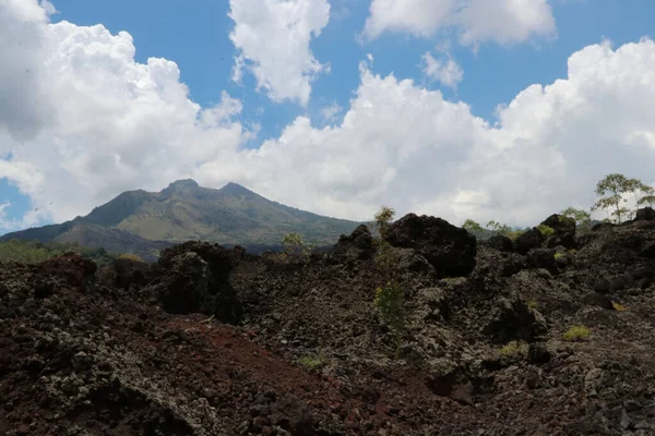 Dağ manzarası, tepeler, dağ kayaları ve beyaz bulutlu mavi gökyüzü.