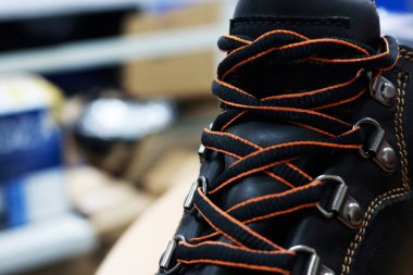 Ayakkabı mağazasında oturan havalı kahverengi deri ayakkabının ayakkabı bağcıklarının fotoğrafı.