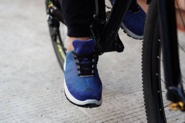 Bisiklet egzersizi yapan ve spor ayakkabısı giyen bir adamın fotoğrafı.   