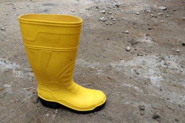 İnşaat işçilerinin ayaklarını korumak için sarı lastik botların fotoğrafı.