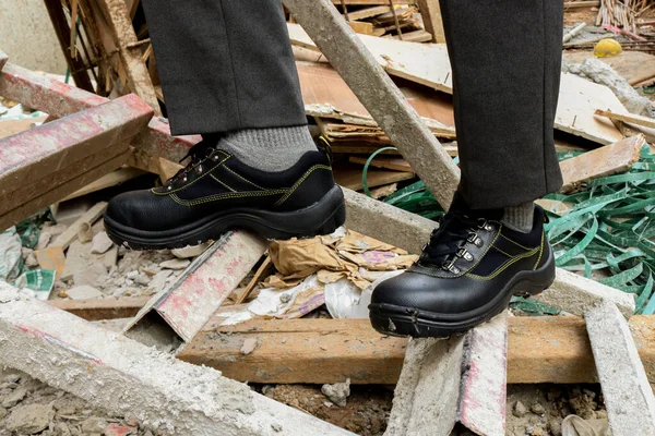 Photo of a construction worker wearing black leather safety shoes at work to protect his feet
