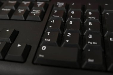 Photo of the black keyboard of a personal computer in an office