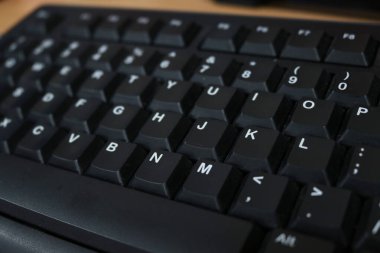 Photo of the black keyboard of a personal computer in an office