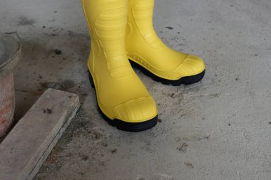 İnşaat halindeki bir binada sarı lastik botların fotoğrafı. Bu lastik botlar su geçirmez ve inşaat işçileri tarafından sıklıkla kullanılır.