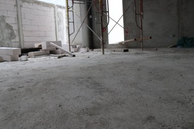 İnşaat halindeki bir binada tuğlalarla döşenmiş ve çimento ve iskeleyle karıştırılmış bir duvar fotoğrafı.