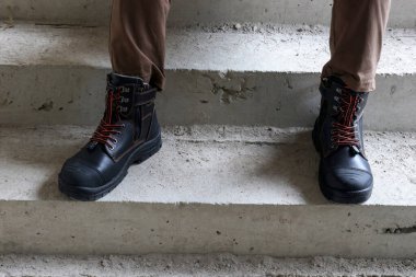 Bir inşaat işçisi çok havalı ve şık görünen kahverengi deri çizmeler giyer.