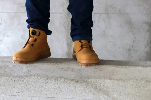 Bir inşaat işçisi çok havalı ve şık görünen kahverengi deri çizmeler giyer.