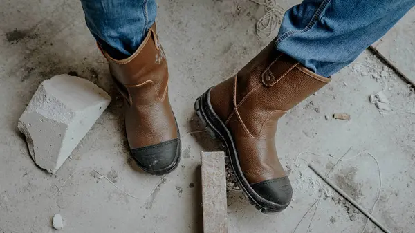 İnşaat işçilerinin ayaklarını iş kazalarından korumak için kullandığı kahverengi deri ayakkabılar.