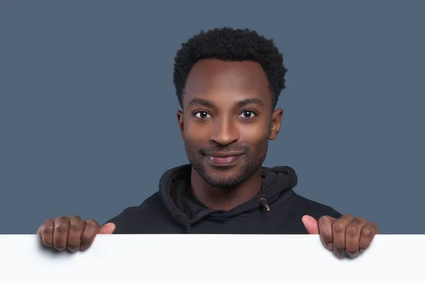 Młody Człowiek Trzyma Białą Stronę Pokazując Puste Tablice Uśmiechnięty Ksero — Zdjęcie stockowe