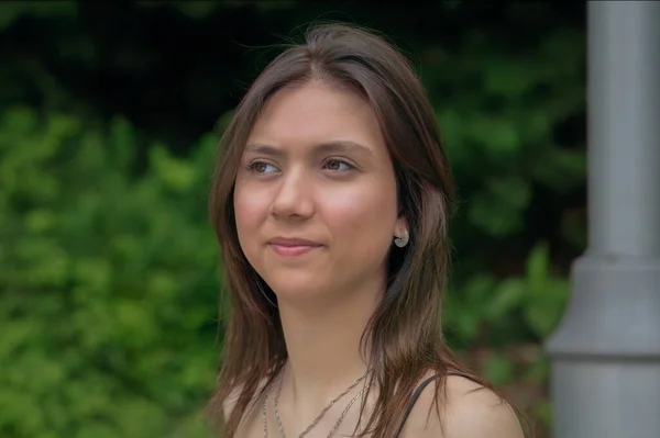 若い女性は脇を見ます学生ネックレス緑の背景プロフィールビューの公園で — ストック写真