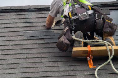 Profesyonel onarım işçisi çatı tamircisi. Güvenli halatla çatıda çalışıyor.