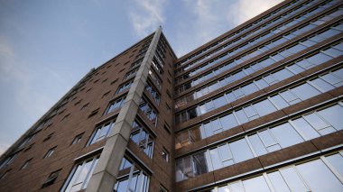 Pürüzsüz tasarımı, geniş açılı pencereleri, yansımalı tuğla manzarası ve büyüleyici bulutlu arka planı olan bir ofis merkezi. 3 Boyutlu resimleme.