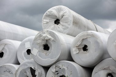 Backfill and rolls of geotextile membrane stacked and packaged in white plastic. Used in construction for insulation, waterproofing, and site protection. Ideal for renovations, basements, lofts, and landscaping. clipart