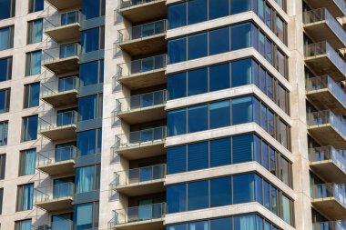 Cam balkonların ve şık mimari tasarımın yer aldığı modern apartman cephesinin yakın plan görüntüsü, kentsel yaşam ve çağdaş stili vurguluyor.