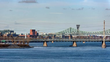 Montreal 'in panoramik gündüz manzarası, Jacques Cartier Köprüsü, Victoria Köprüsü ve St Lawrence Nehri üzerindeki Olimpiyat Stadyumu. Şehir simgelerini ve ufuk çizgisini vurgular.