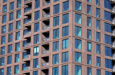 Beton ve cam balkonların ve zarif mimari tasarımın yer aldığı modern apartman cephesinin yakın görüntüsü, kentsel yaşam ve çağdaş stili vurguluyor.