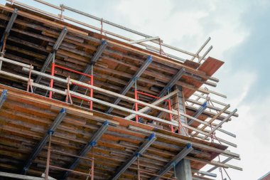 Kısmen inşa edilmiş beton bina, ahşap biçimlendirme ve destek kirişleri, modern inşaat yöntemleri ve yapısal gelişim sergileniyor.