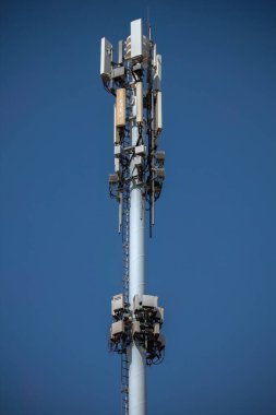 Birden fazla anten ve iletişim ekipmanına sahip baz istasyonu, canlı mavi gökyüzüne karşı modern telekomünikasyon altyapısını gösteriyor..
