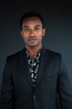 Siyah stüdyodaki genç adam siyah takım elbiseli ve gömlekli yakışıklı adam başarılı bir iş adamı.