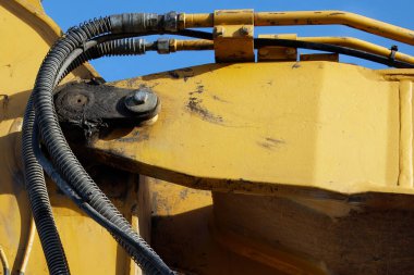 İnşaat işlerinde kullanılan ağır makinelerin detaylarını vurgulayarak, hidrolik hortumları, metal eklemleri ve endüstriyel aşınmaları gösteren bir kazıcı kolunun yakın çekimi.