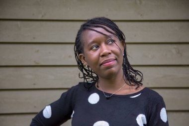 Düşünceli Afrikalı kadın dışarıda ayakta duruyor, hayal kuruyor ve dalgın dalgın yukarı bakıyor. İlham, yaratıcılık, farkındalık ve kişisel yansıma temaları için ideal.