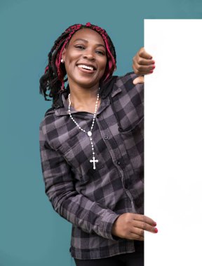 Ekose gömlekli mutlu Afro-Amerikalı kadın elinde beyaz bir tabela tutuyor. Reklamlar, reklamlar, duyurular, pazarlama materyalleri ve kişiselleştirilebilir mesajlar için mükemmel..