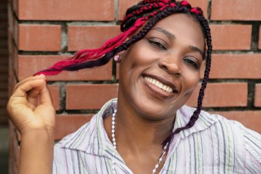 Çizgili tişörtlü, canlı, koruyucu saç stiliyle gülümseyen bir kadın. Saç bakımı ve güzellik anlayışı için mükemmel.