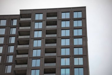 Temiz geometrik tasarımı ve çoklu balkonları olan modern apartman dairesi. Simetrik pencere desenli çağdaş kentsel mimari.